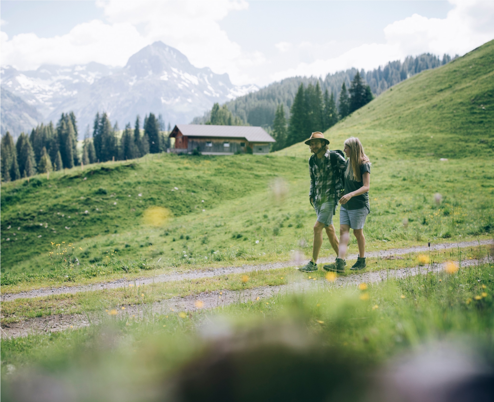 Ein junges Paar auf einer Wanderung mit dem Berggipfel im Hintergrund.