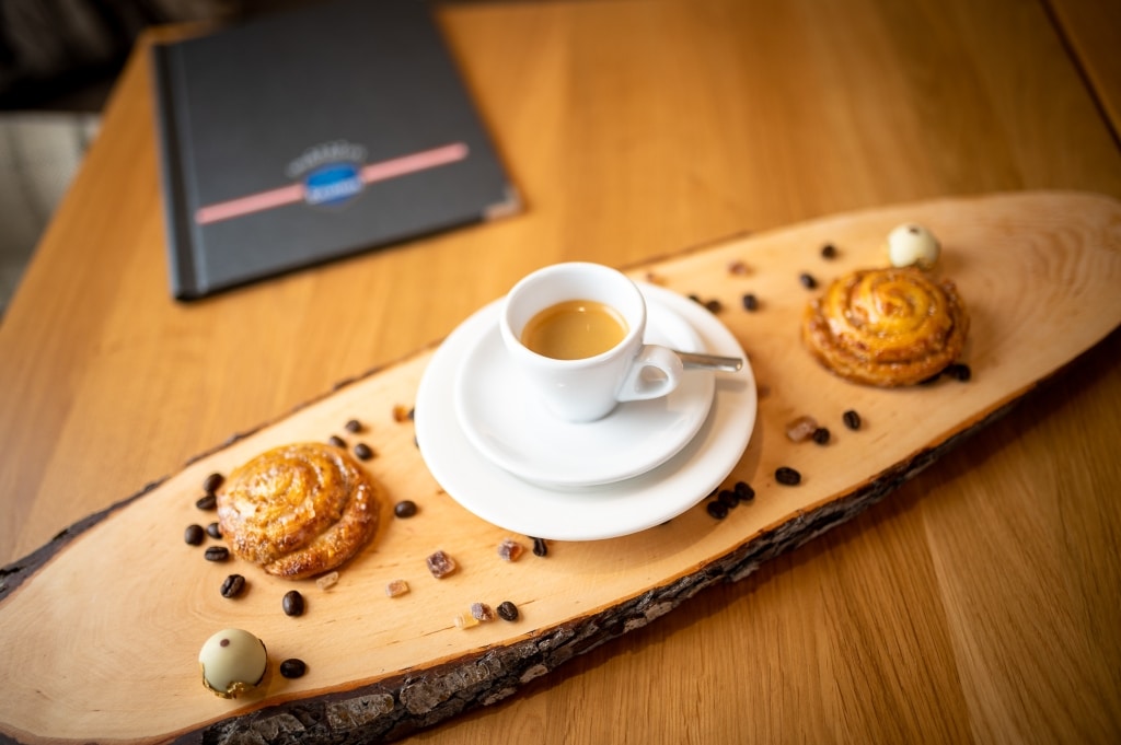 Eine schicke Präsentation einer kleinen Tasse Espresso in Szene gesetzt mit zwei frisch gebackenen Backwaren.