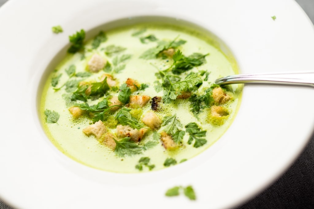 Eine Gourmet-Suppe mit Gemüse und frischen Croutons, serviert in einer weißen Schleife.